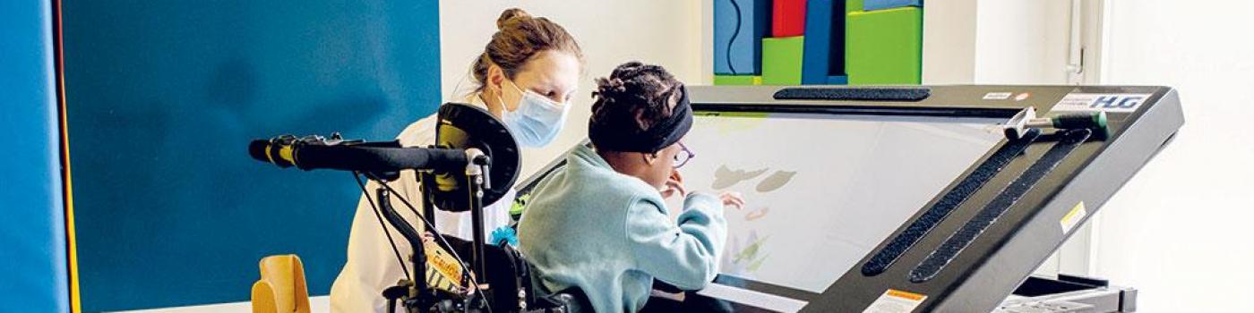 Petite fille jouant avec écran tactile accompagné par une pédiatre