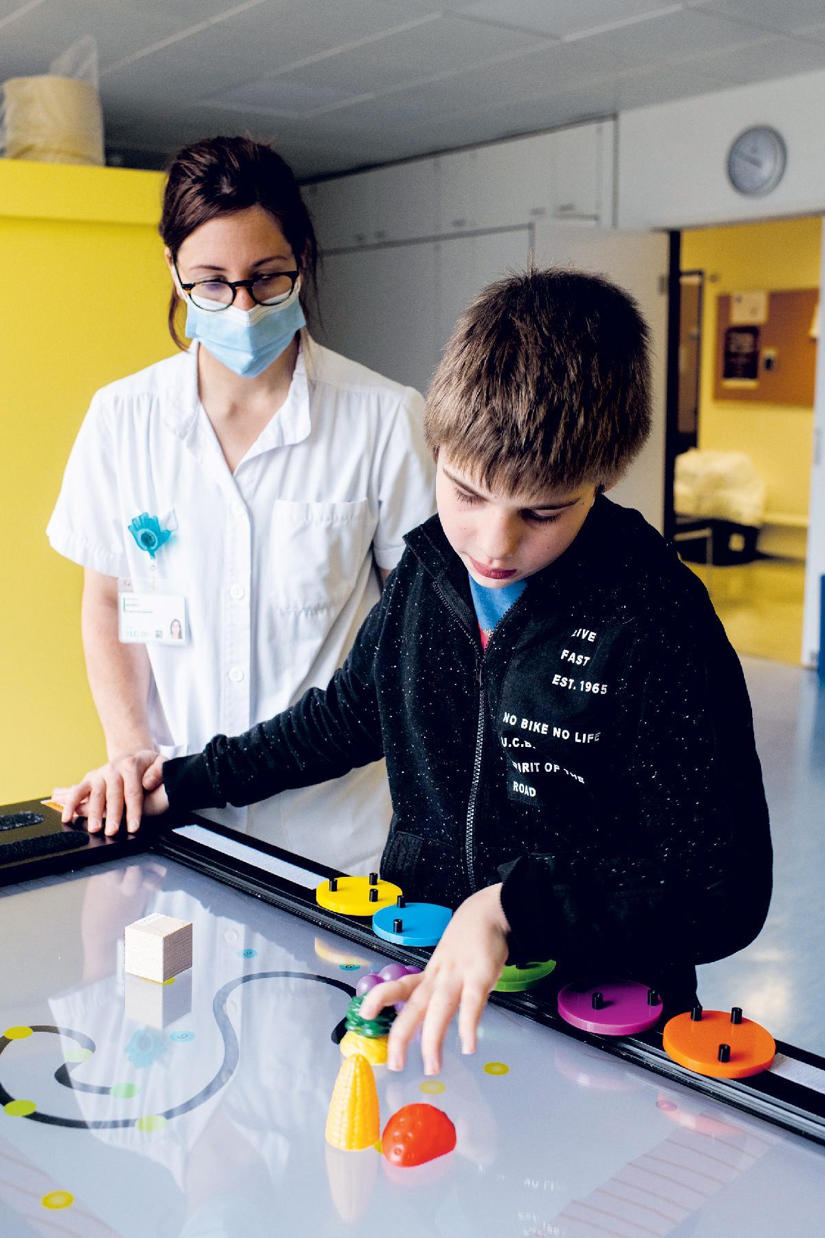 Une première en Suisse Un enfant joue avec l'écran tactile accompagné par une pédiatre