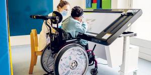 Petite fille jouant avec écran tactile accompagné par une pédiatre